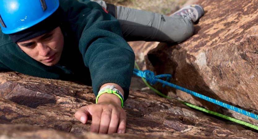 a person in rock climbing gear climbs up a rock wall in texas